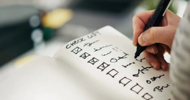 Profesional revisando lista de requisitos en oficina con portátil abierto