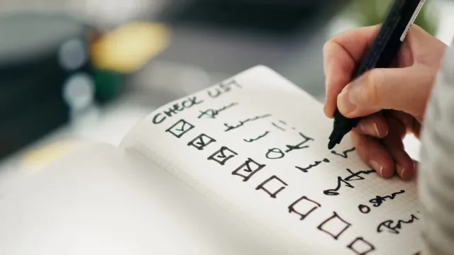 Profesional revisando unha lista de requisitos nunha oficina co portátil aberto