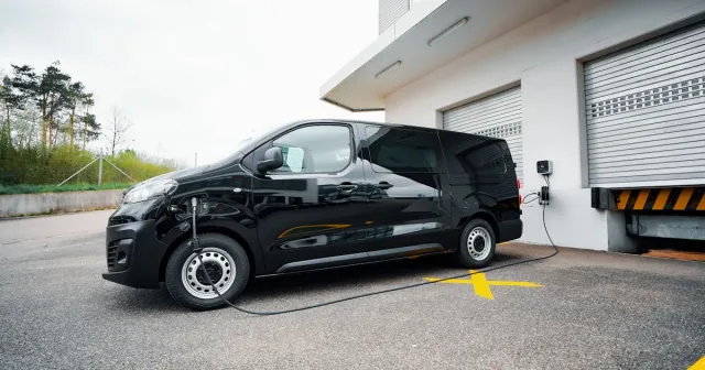 Furgoneta eléctrica conectada a punto de carga rápida en hub logístico