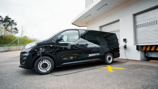 Furgoneta eléctrica conectada a un punto de carga rápida nun hub loxístico